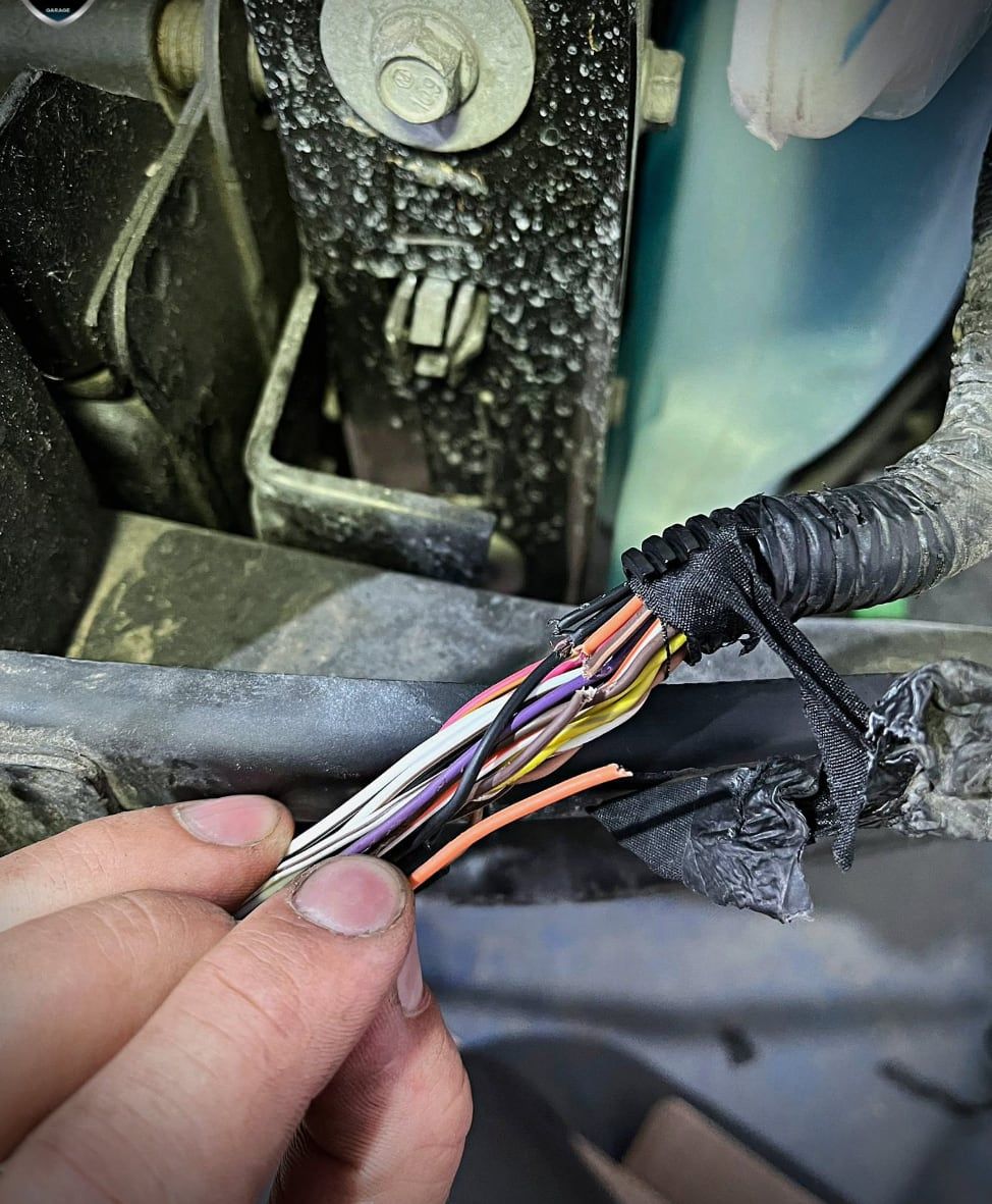 Mechanik trzyma rozplecione przewody wiązki elektrycznej podczas naprawy